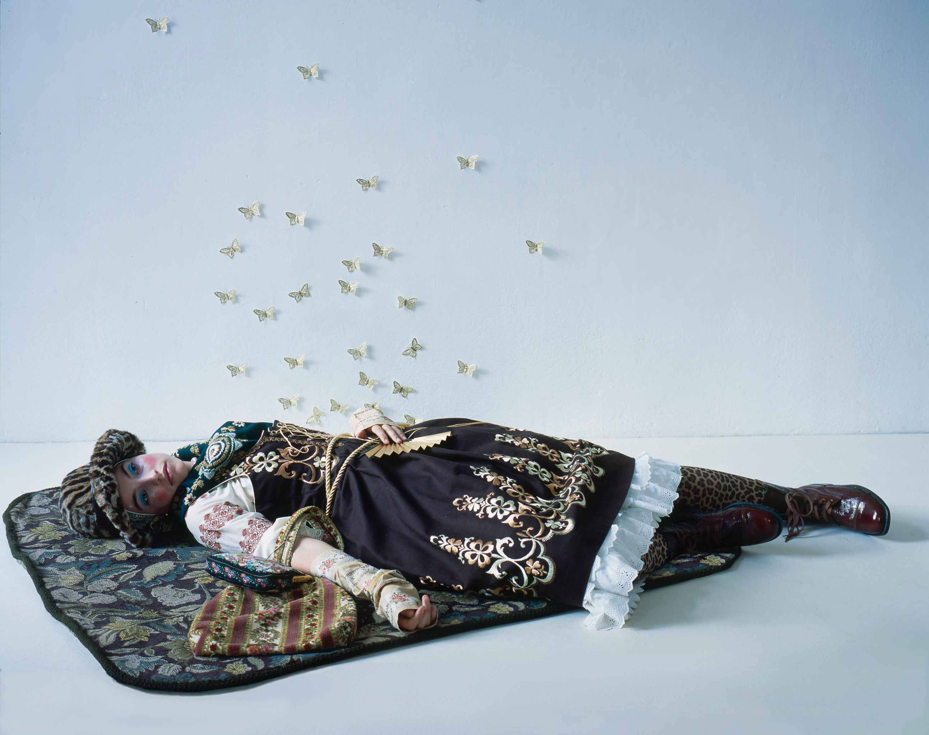 Woman dressed in folklore dress mash-up lying on fabric.