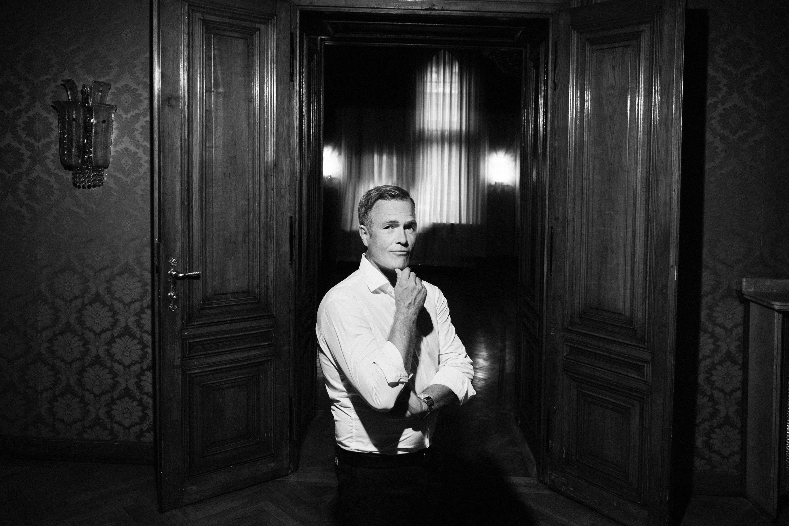 B/W photo. Man inside old emperor's building stands in front of door to magnificent hall.