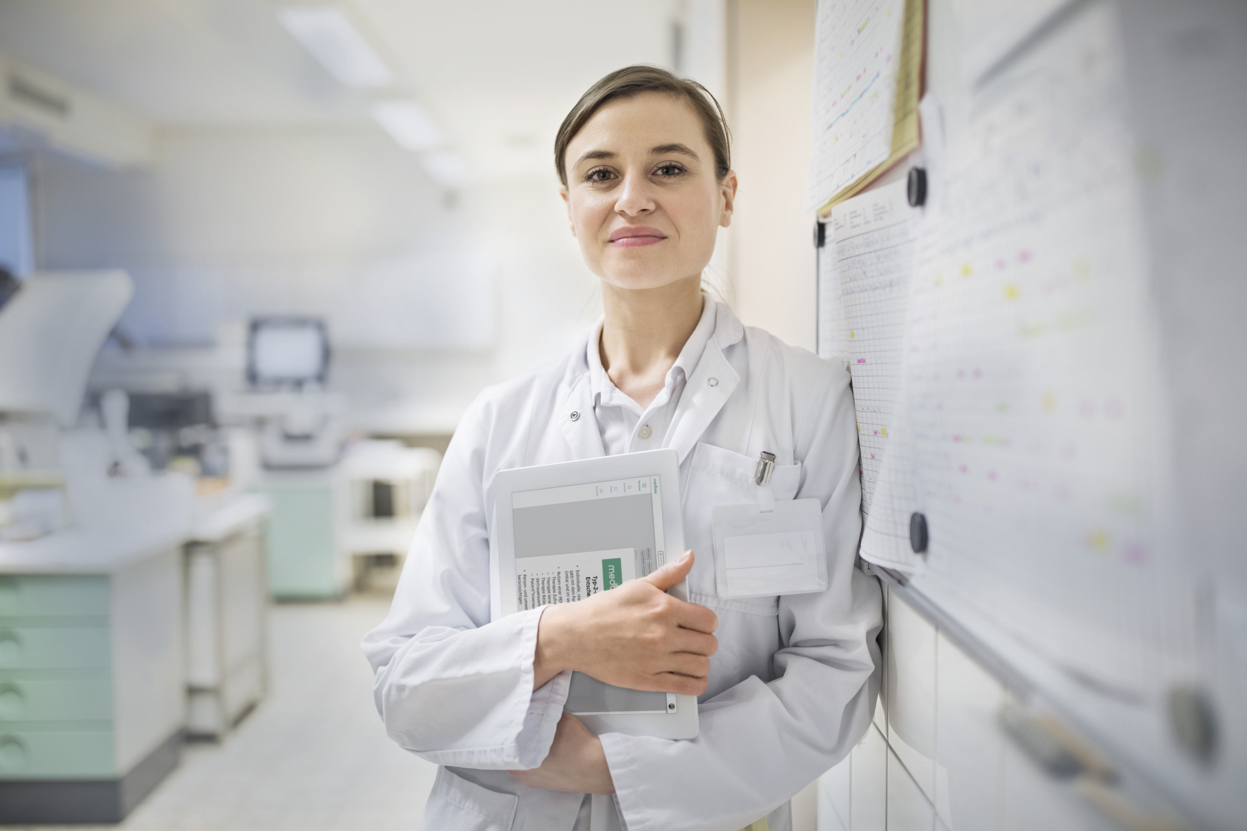 Female doctor standing inside a laboratory in hospital. Holding tablet.