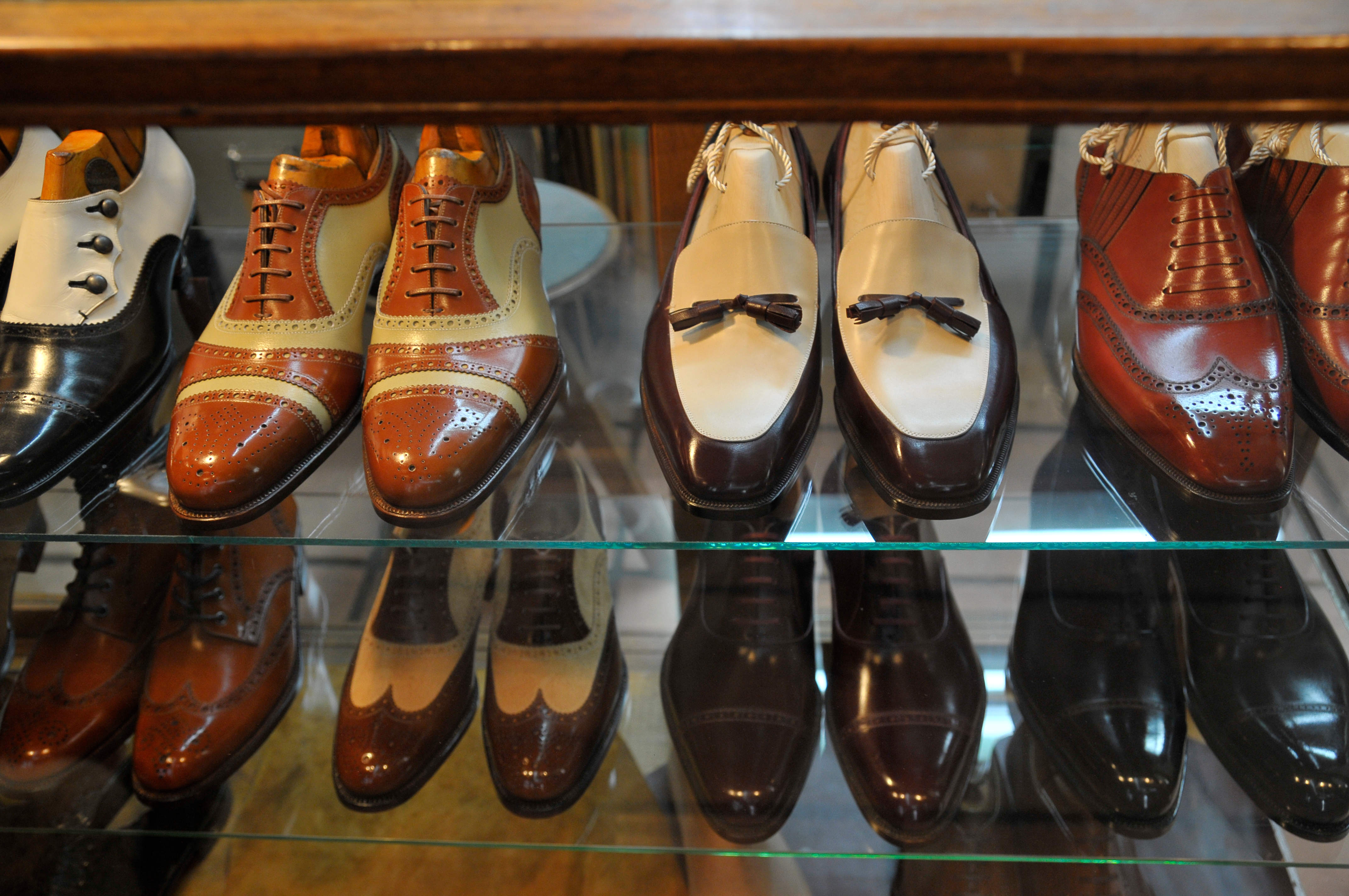 Several polished elegant shoes inside glass cabinet.