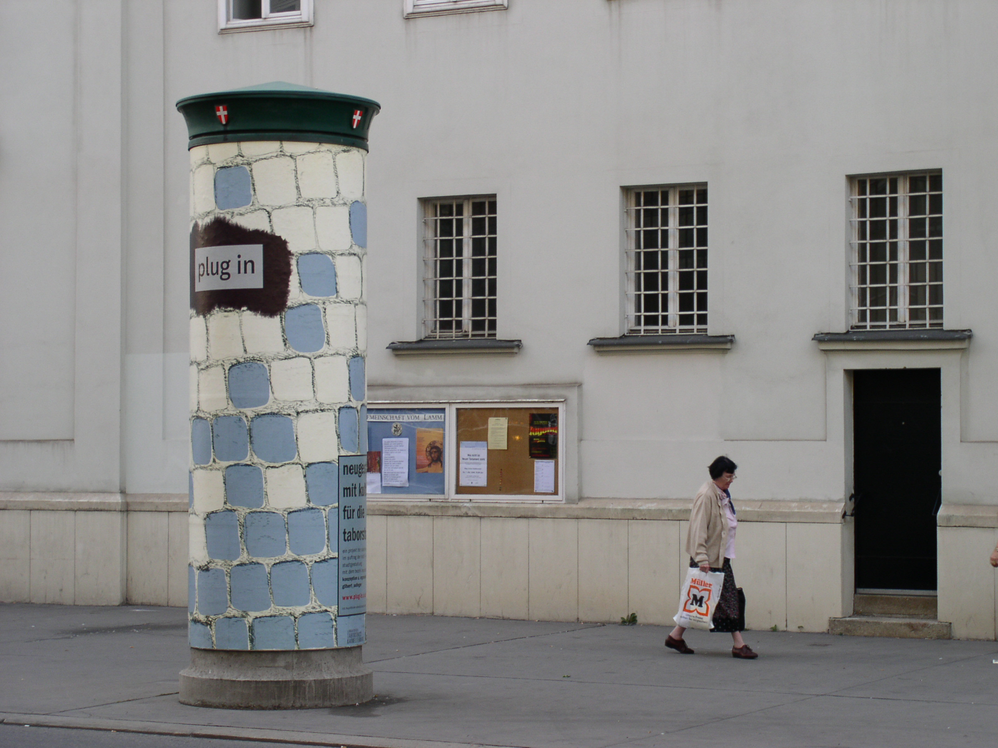 One side of large advertising pillar in the street. Completely wrapped with poster. Illustrated cobblestone floor allover. Logo overlayed on upper half.