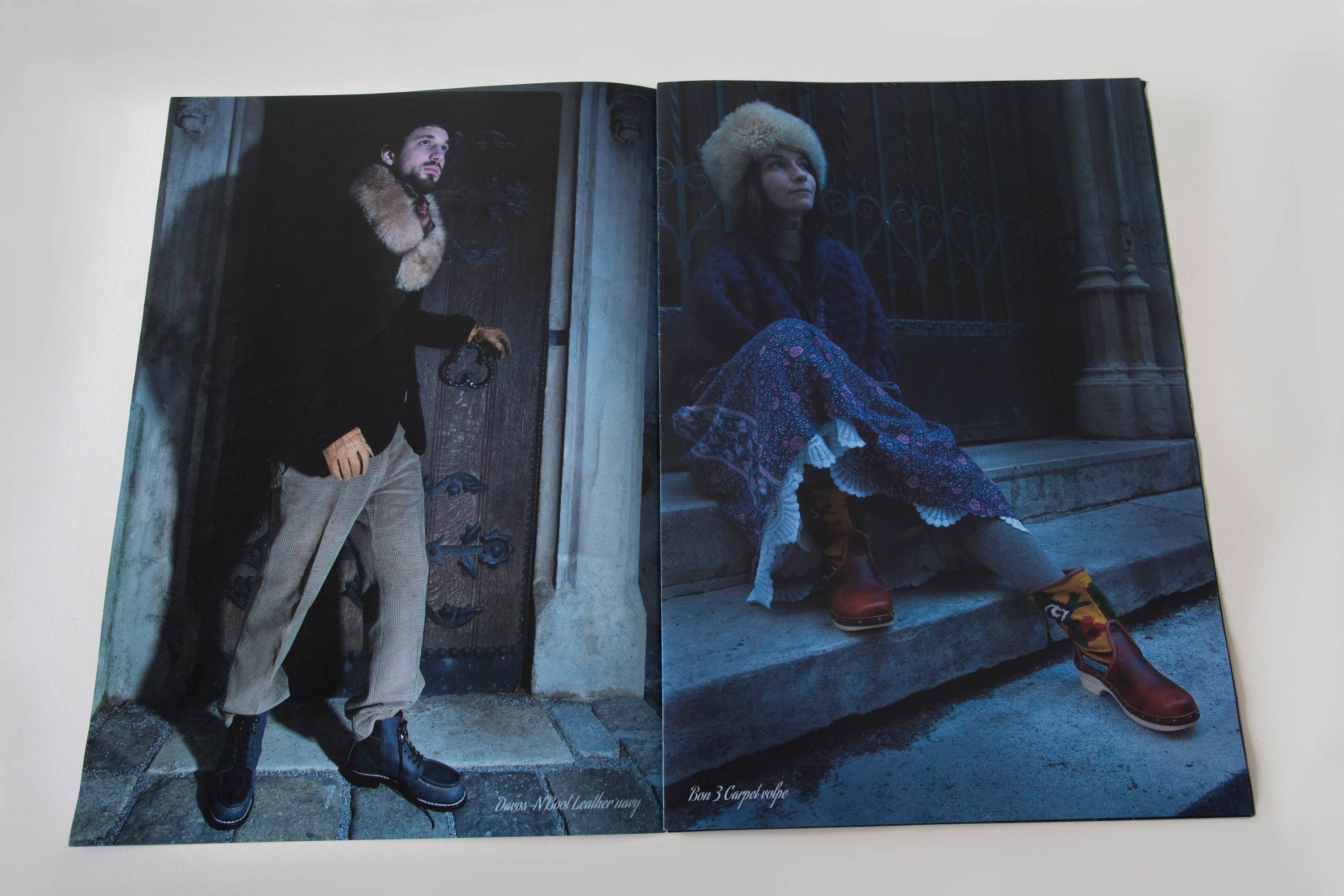 Double page showing full-page night shots. Small script font overlayed at bottom. Left page: Man standing in front of medieval wooden door. Right page: Woman sitting on stone steps in front of heavy medieval metal door.