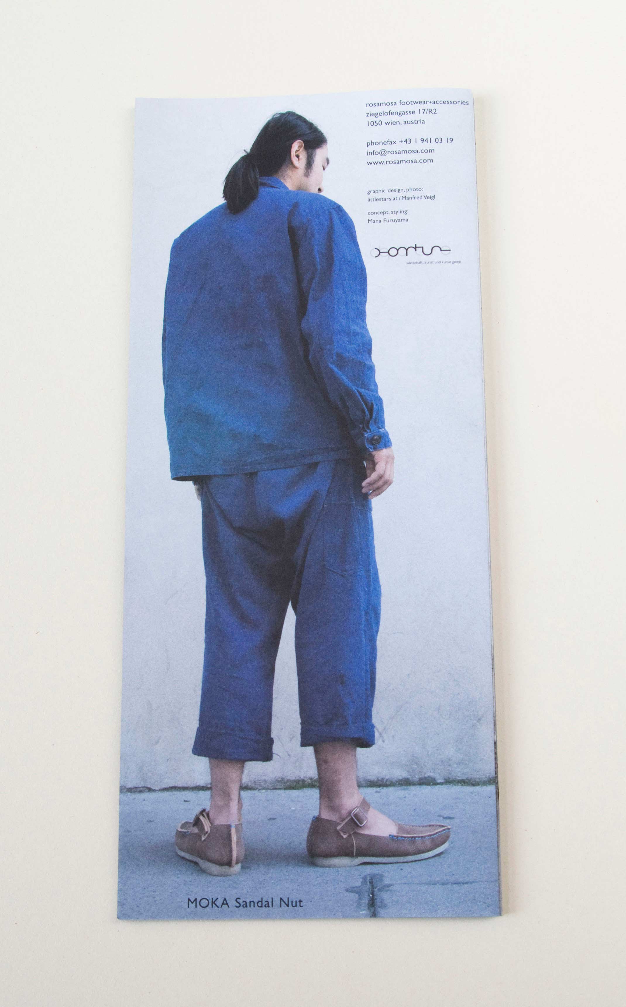 Back of zig-zag folded catalogue. Full-page photo of man turned away standing on the street on front of white wall. Small blocks of text overlayed.