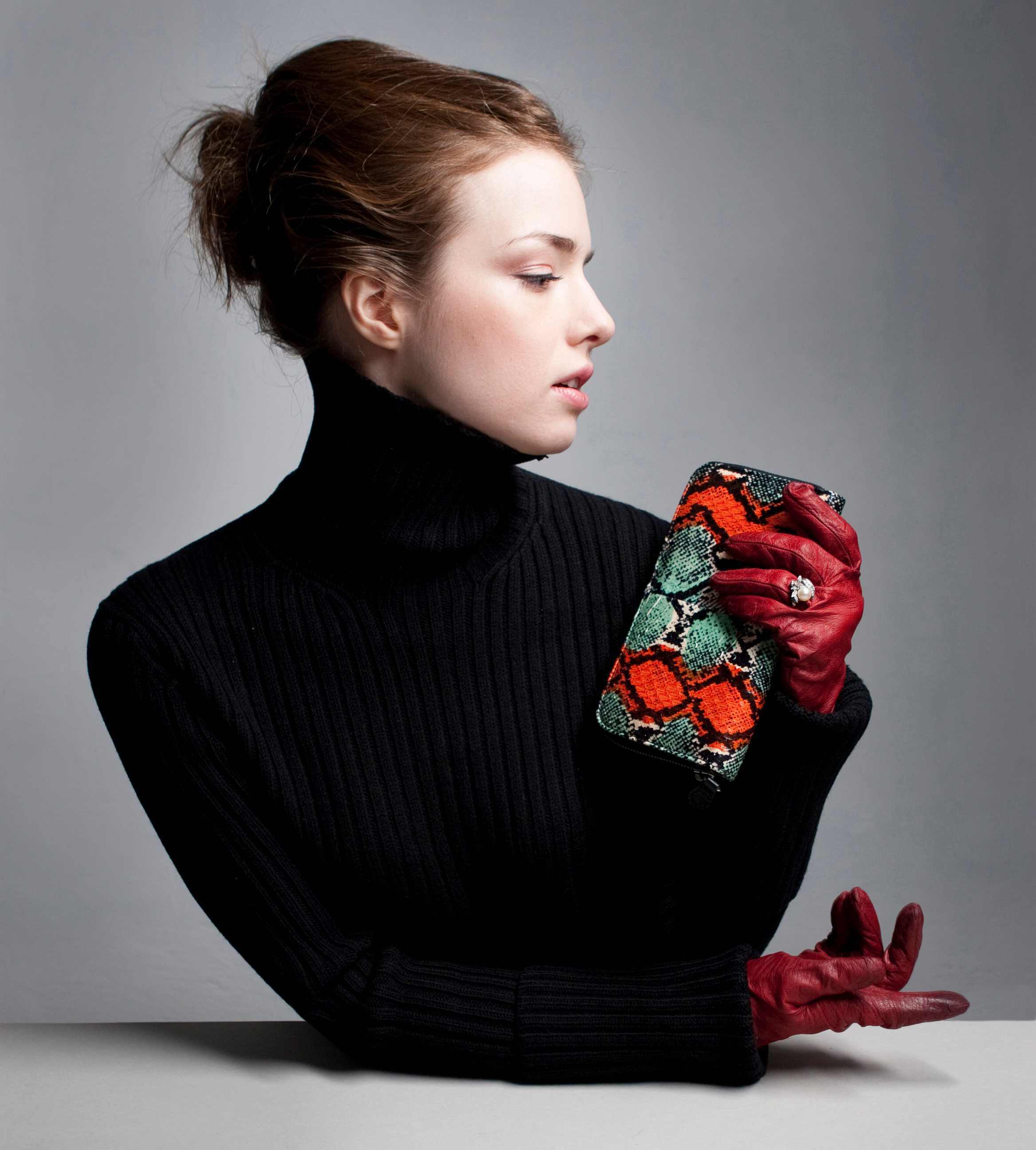 Woman wearing elegant red leather handgloves holding large purse.