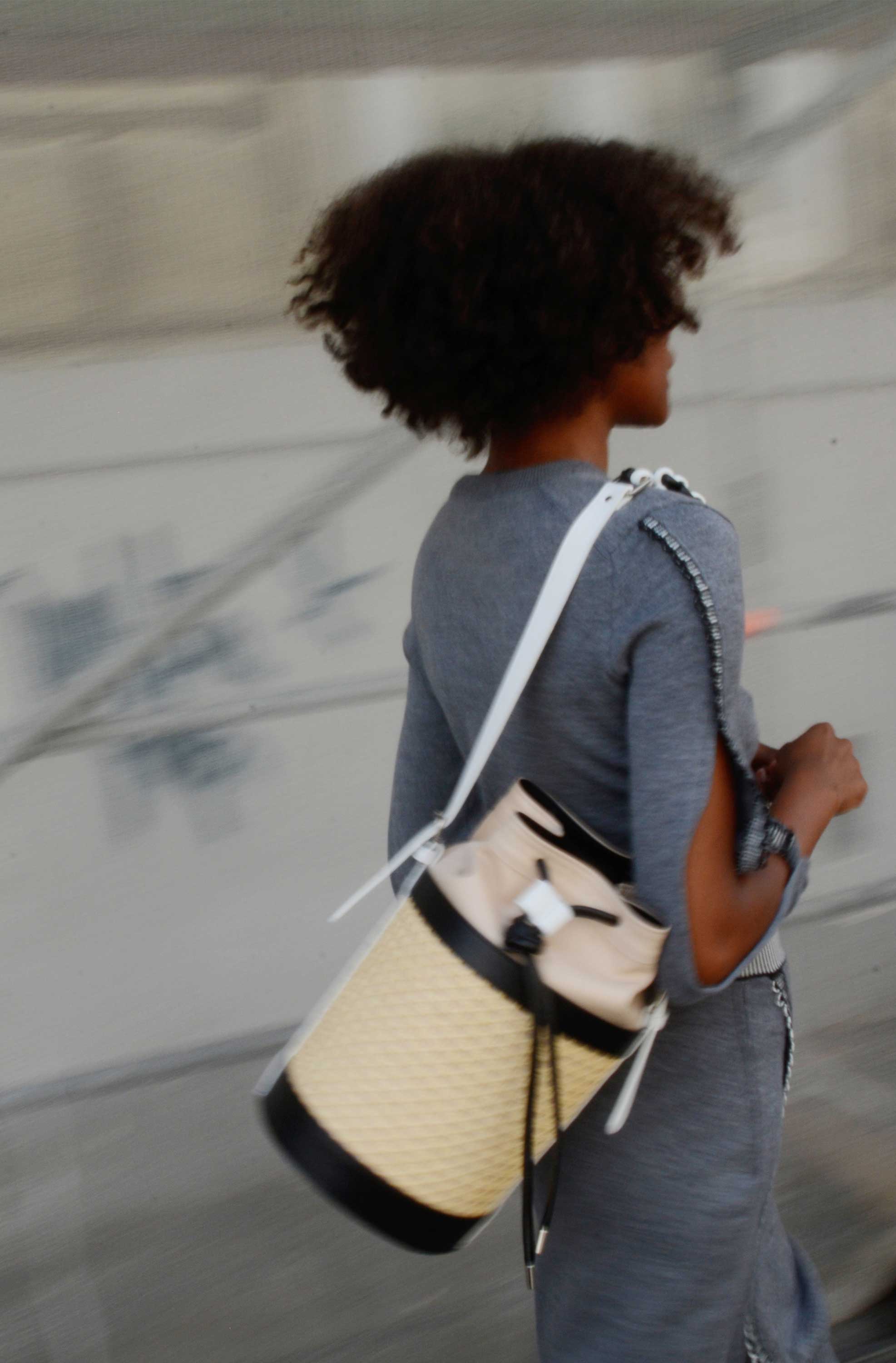 Woman running on the street. Carries handbag around her shoulder.