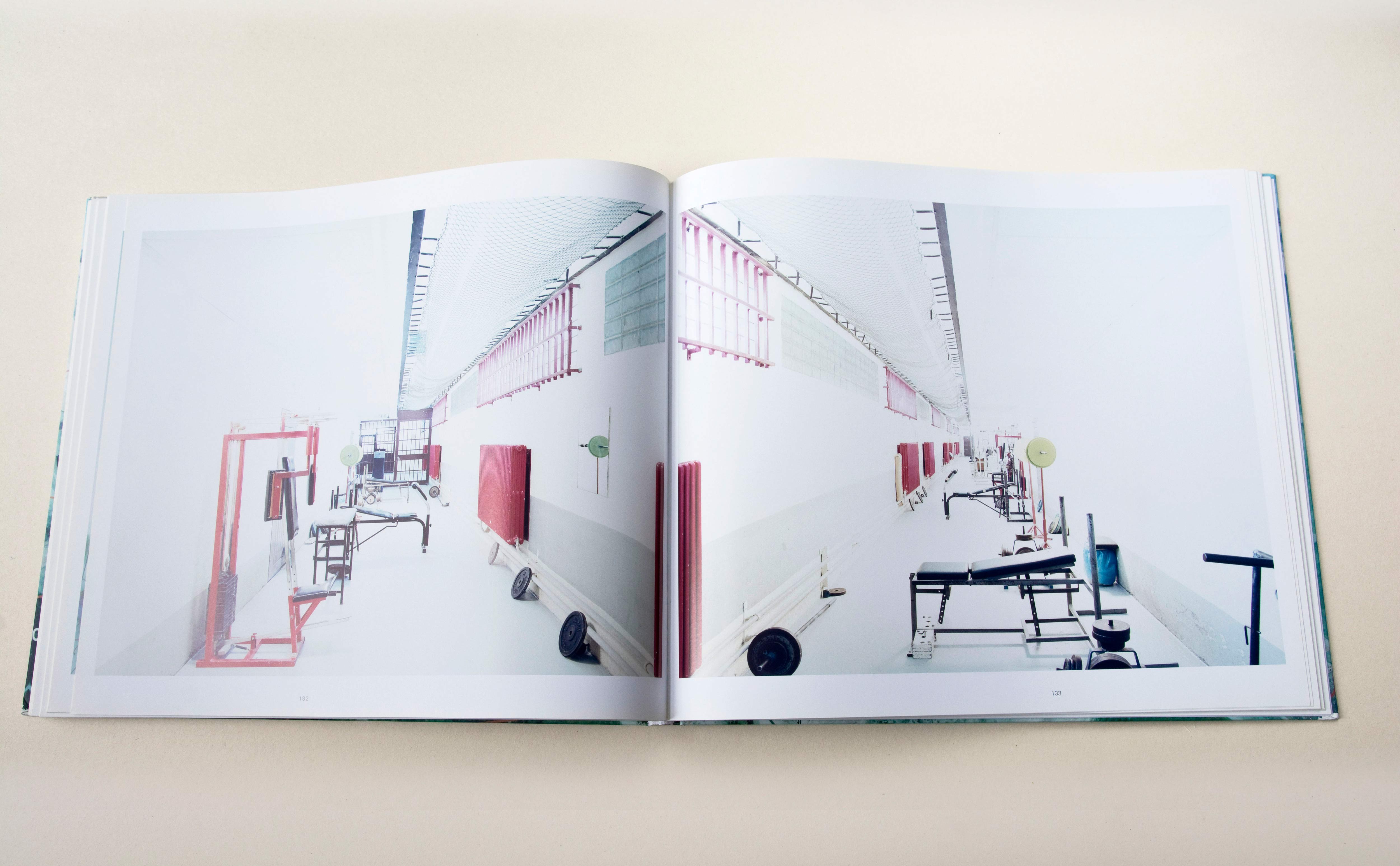 Double page. Large photo with white space around on each page. Left: Grey brick wall in construction. Right: Inside a building made of grey bricks.