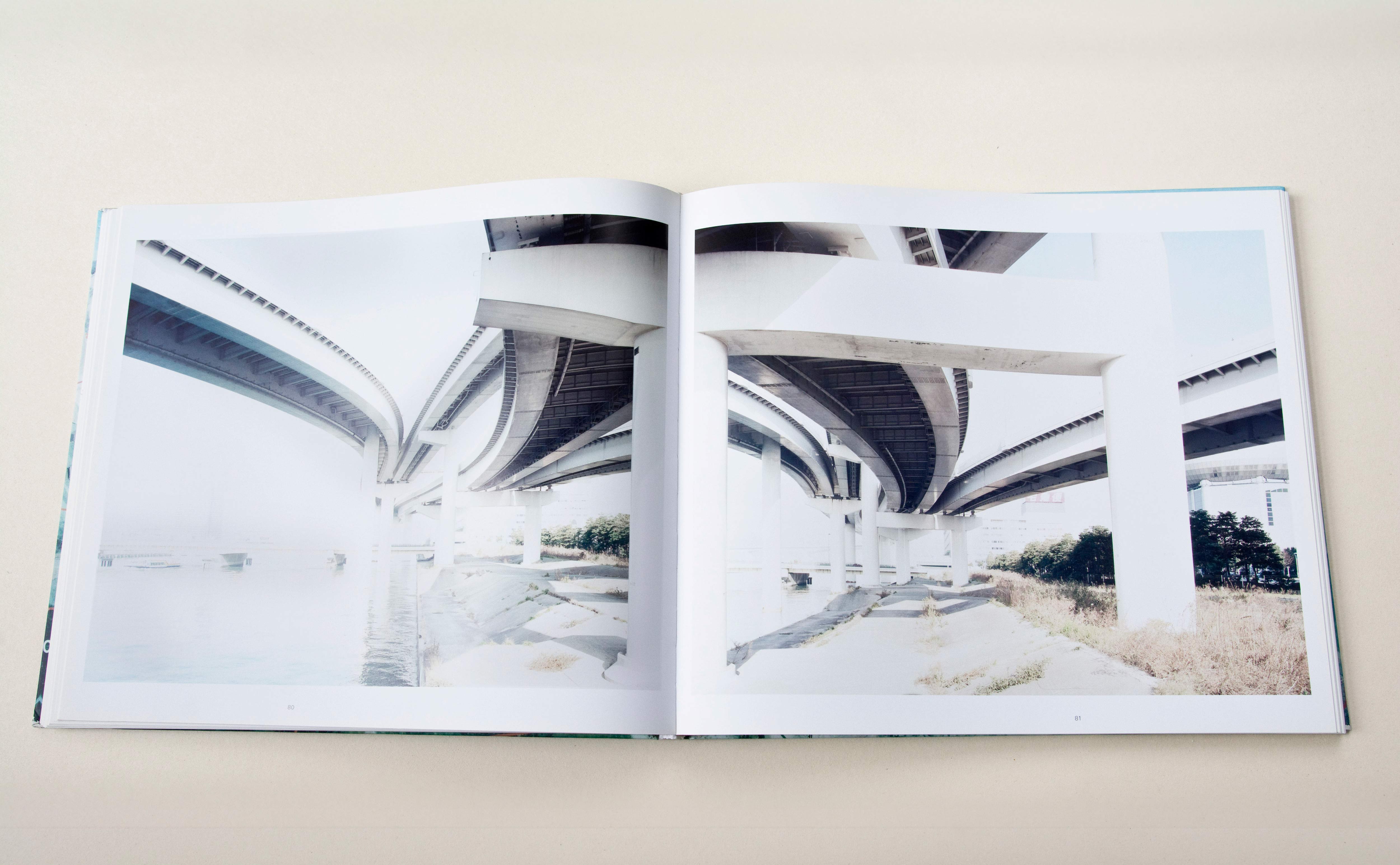 Double page. Large photo with white space around on each page. Left: Corridor in a prison. Fitness devices standing at the side. Right: Similar shot of corridor mirrorerd.